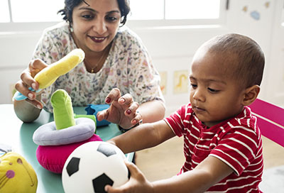 Young child playing with teacher in the classroom