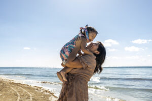 Mother and daughter having fun on the beach. They are enjoying sunny day outdoors