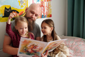 一位父亲与他的两个小女儿一起阅读图画书